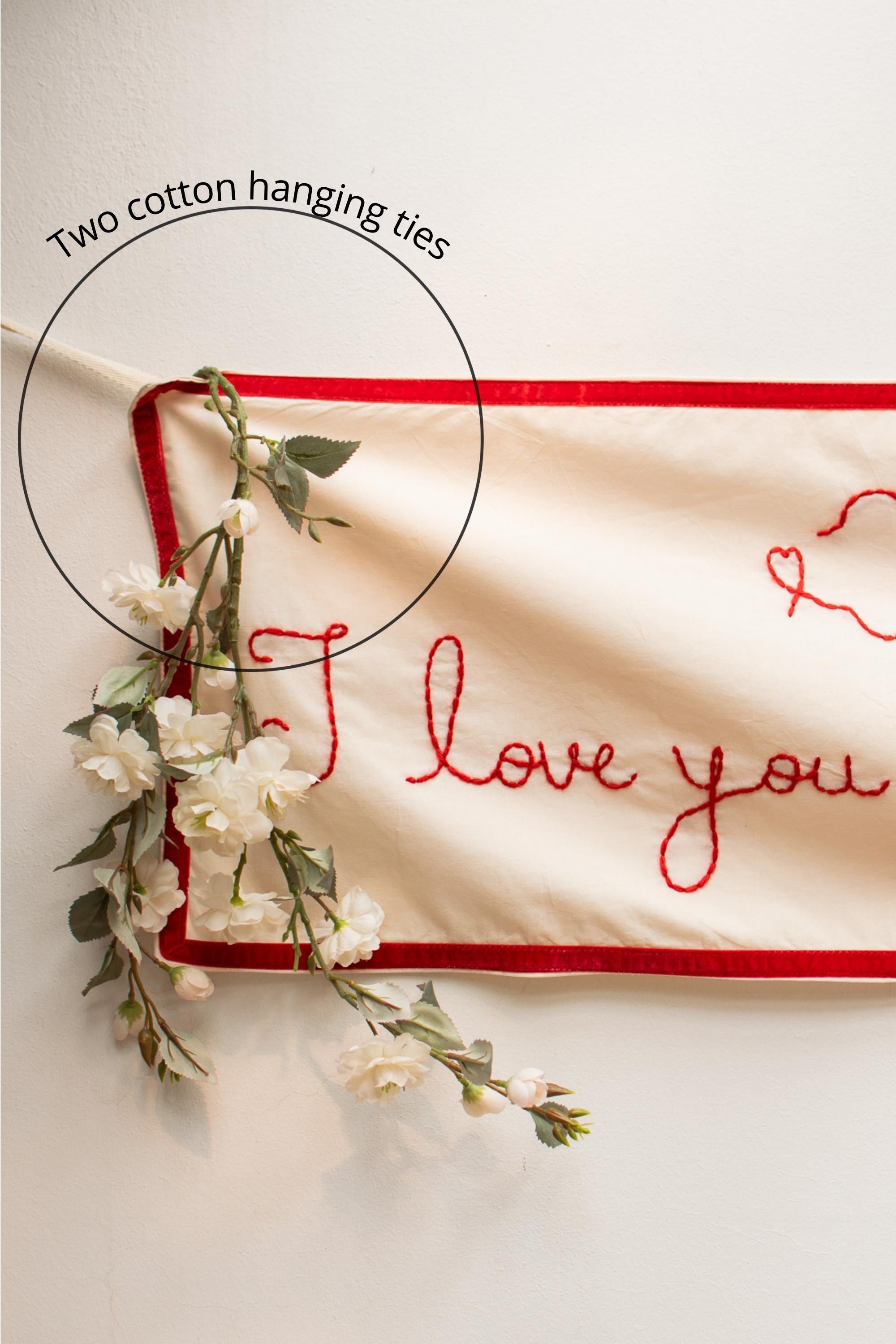 Two cotton hanging ties with floral decorations and 'I love you' embroidery on a light background.