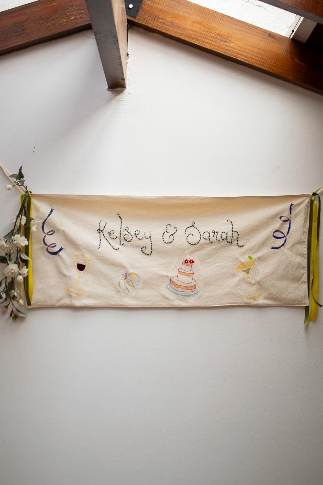 Beige illustrated wedding banner with blue and yellow satin ribbons and white flowers